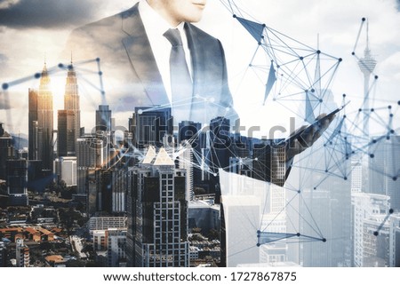 Businessman using tablet with creative polygonal hologram with city view background. Communication and teamwork concept. Multiexposure