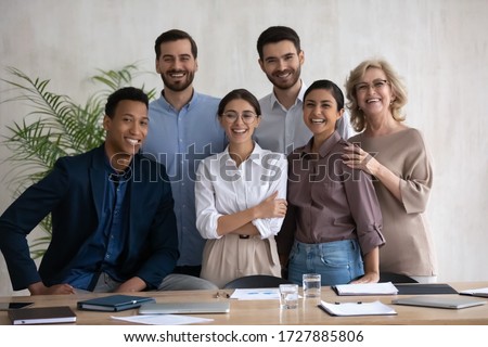 Portrait picture of smiling diverse employees stay together laughing looking at camera. Happy businesswoman with african american and caucasian businessmen, mature and indian ethnic female colleagues.