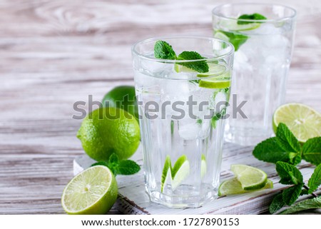 Cold refreshing summer lemonade mojito in a glass on white wooden background