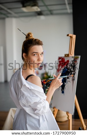 Young beautiful woman in a white shirt draws a picture