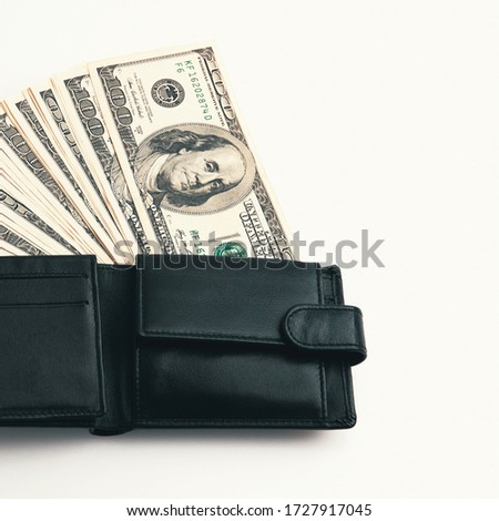 A black wallet with dollars in it on a white background.