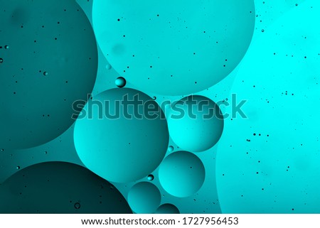 Beautiful and fantastic macro photo of water droplets in oil with a blue background.