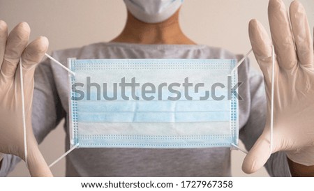 Woman with a medical mask and hands in latex gloves holding protective medical mask. 