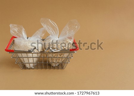 various groats in packages in a grocery basket on a brown background. Rice and oatmeal
