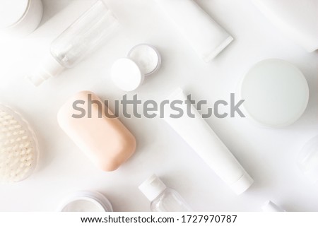 White squeeze tube, bottle of cream, shampoo, soap, cleanser, body brush, empty container flat lay on white background top view. Beauty skincare, natural cosmetic, daily products. Stock photo