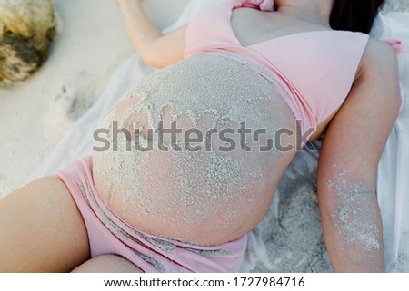 Beautiful asian young pregnant woman wearing pink bikini is lying on the beach at Phangan island in evening time. Selective focus and split color.