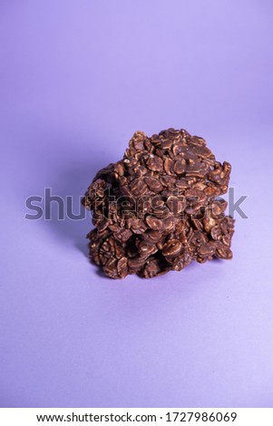 Oatmeal cookies pile with chocolate powder and peanut butter on purple background. Healthy snack. Top view. Vertical picture.