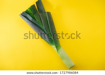 Green leek isolated on yellow background. Conceptual picture. Healthy life.