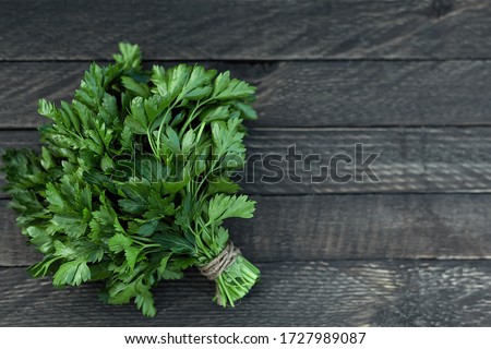 On a wooden background is a bunch of green fresh fragrant parsley. Royalty-Free Stock Photo #1727989087