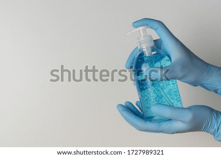 Hands in medical gloves with hand sanitizer in a bottle on white background. Coronavirus prevention concept.