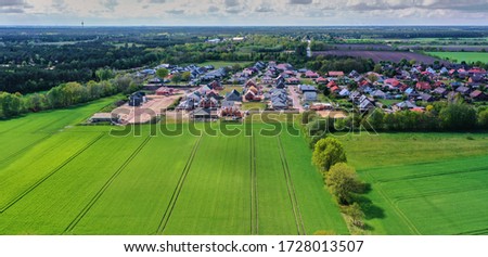 Aerial view of a development area with carcasses for single-family houses at the edge of a green field