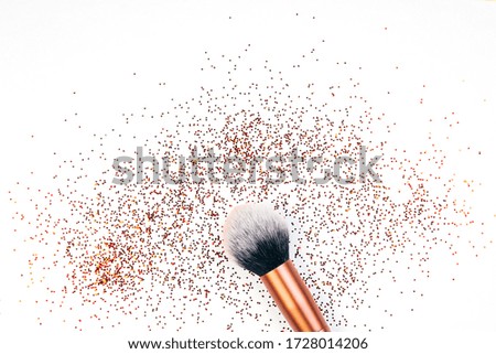 Makeup brush and golden sparkles on white background,