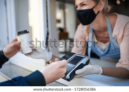 Woman with face mask serving coffee through window, shop open after lockdown. Royalty-Free Stock Photo #1728056386