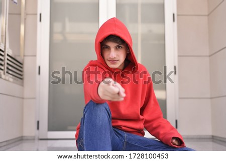 portrait of smiling young man in red clothes pointing his index finger.