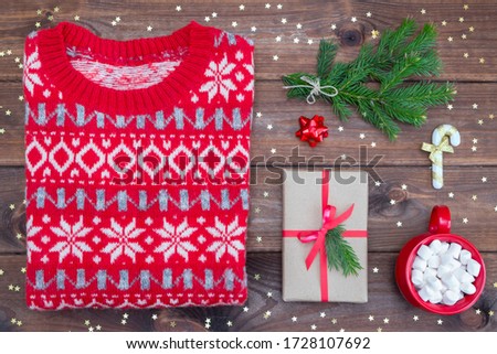 Top view christmas sweater, mittens, gift and coffee with marshmallows and decorations on a green background. Flat lay.