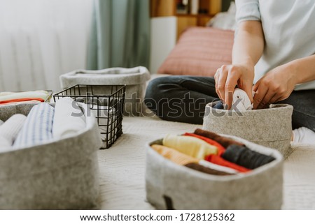 Woman folding clothes, organizing stuff in boxes and baskets. Concept of minimalism lifestyle and japanese t-shirt folding system. Minimalist storage and arrangement in wardrobe Royalty-Free Stock Photo #1728125362