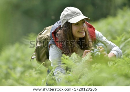 Young woman taking pictures during walk in nature