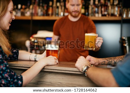 Young ginger barman serving beer to his customers.
