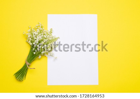 Top view of a white paper letter and flowers on yellow  background, copy space
