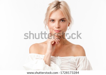 Image of beautiful thinking woman in earrings posing and looking at camera isolated over white background