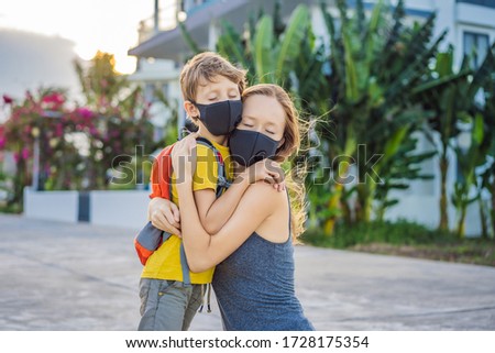 mom hugs a sad son on the sidewalk in the city. Mother and baby wear face mask during coronavirus and flu outbreak. Protection against viruses and diseases, quarantine period