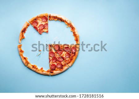 Above view with a delicious homemade pepperoni pizza. Home-baked pizza crust on a blue background top view. Pizza leftovers. Royalty-Free Stock Photo #1728181516