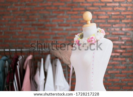 Copy space banner of manikin with rose and measuring tape, textile and fashion designing concept, in home office studio working design clothing and dress , with red brick wall texture background