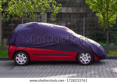 The car is wrapped in a cover from precipitation, dirt. Protective material when standing in one place for a long time. Vehicle Protected From Weather. Royalty-Free Stock Photo #1728233761