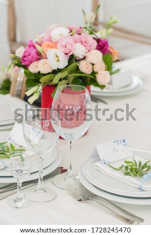 Serving the table with plates, glasses and a box with a bouquet of roses
