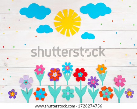 Composition of colorful summer flowers, sun, clouds from multi-colored paper, step by step. Child make crafts his own hands. Cute DIY handmade art creativity on a wooden table. Top view, copy space