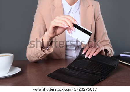 A plastic card for paying for purchases in a woman's hand. An unrecognizable photo. Top view. Copy space.