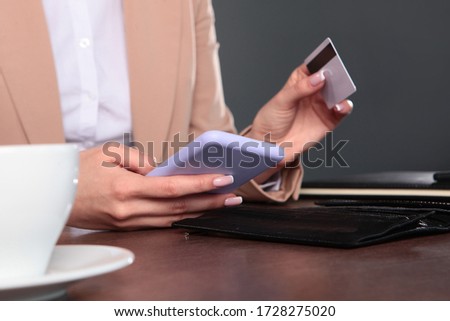 A woman is sitting at a Desk and shopping online. An unrecognizable photo. Copy space.