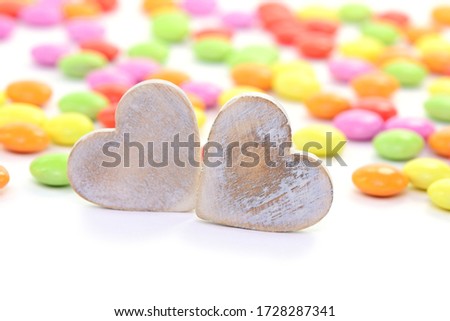 Two wooden hearts, colorful sweets on white background, closeup. 