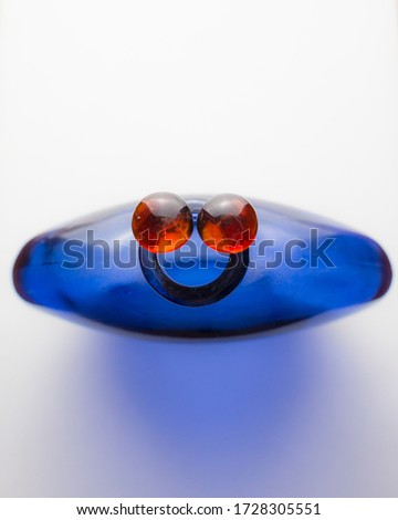Face-Like Image of Blue Bottle with Red Marbles for Eyes. Concept of Cute. Copy Space of Smiley Face.