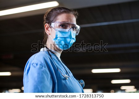 Young female UK NHS doctor in lab or hospital clinic,worried and anxious,tired and exhausted after long shifts,Coronavirus COVID-19 pandemic crisis causing stress and shortage of staff,ICU EMS worker Royalty-Free Stock Photo #1728313750