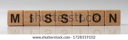 concept of mission word on wooden cubes on grey glossy background with reflection