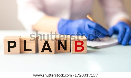 Word PLAN B on wooden building blocks and blurring hands in medical gloves on white background.