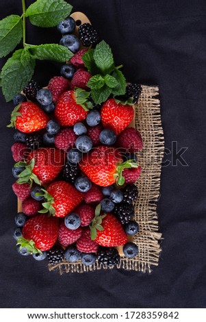 Variety of summer  berries, fruits on black canvas background. Dramatic  kitchen concept Royalty-Free Stock Photo #1728359842