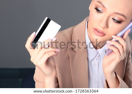The girl is on the phone and holding a plastic card in her hand. Concept of purchases by Bank transfer. Top view. Copy space.