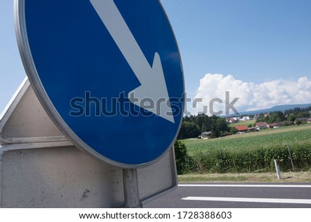 Direction road sign on a country road, arrow pointing to the right