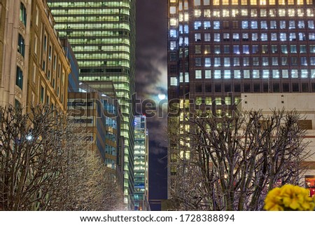 Super moon shining London skyscraper in a cloudy night, England, UK