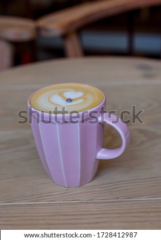 A Cup of hot cappuccino coffee on wooden table. Autumn mood concept. Winter mood concept. Warm autumn or winter picture. Selective focus. At home. Time for relax. Pink cup with latte on the table