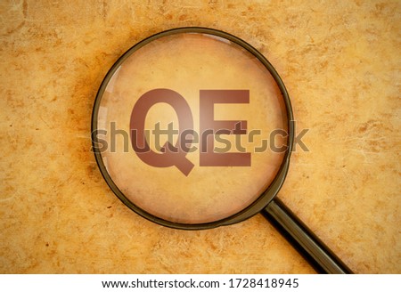 Magnifying glass focusing on QE for quantitative easing  Royalty-Free Stock Photo #1728418945