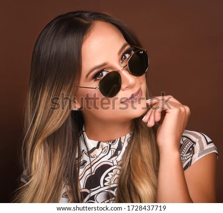 Charming young woman with sunglasses and luxurious hair. Studio portrait.