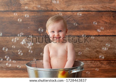 One year old baby takes a bath. Bathed in a basin with rubber ducks.