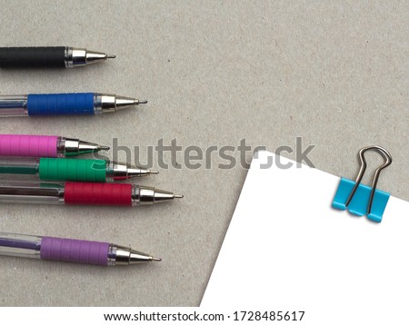 Colorful pens and blank notepad on kraft background.