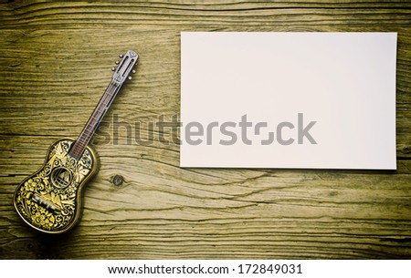 Vintage guitar on old wood surface and blank piece of paper