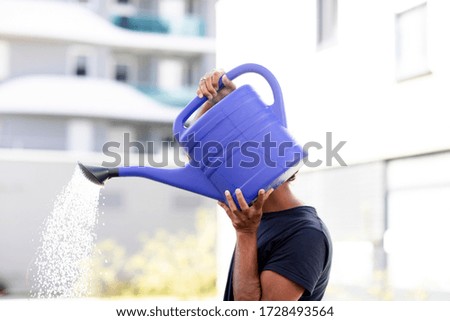 young man with watering can outside