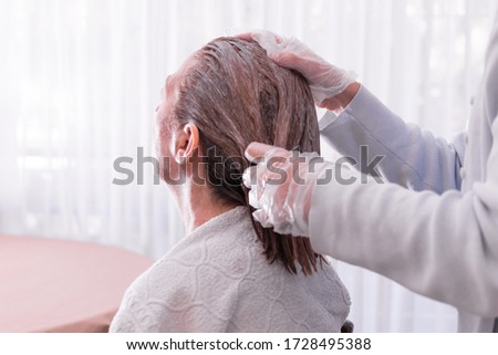 Image representing personal care at home. woman massaging the hair of a woman in blond color in order to dye. Indoors. Close up photo of hair. Personal care in time of coronavirus disease. No faces.