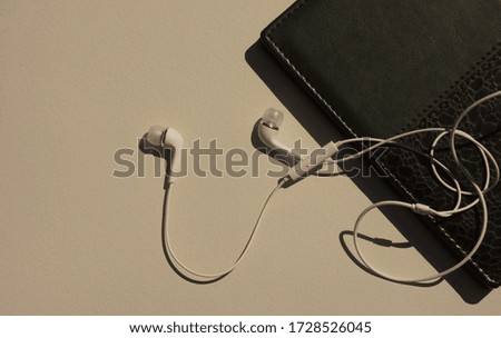 audiobook and white headphones lie on a bright background                              